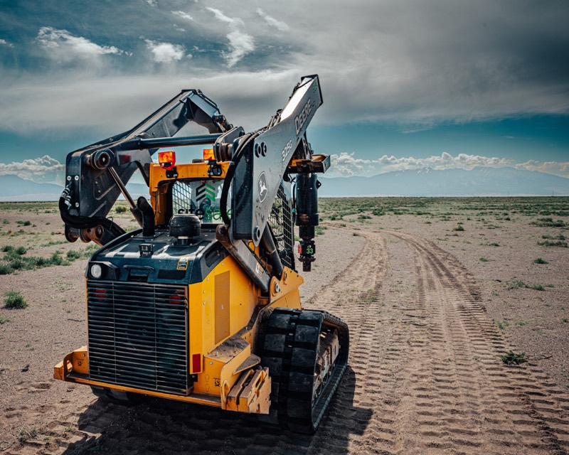 Tracked loader fitted with a pier drive head on an open job site