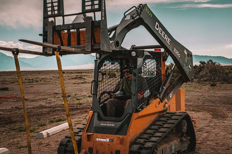 Track loader with a helical pier drive head on a job site