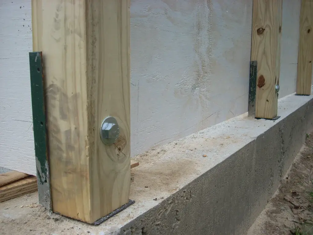 Wood posts strapped and bolted to a narrow cast-in-place concrete grade beam